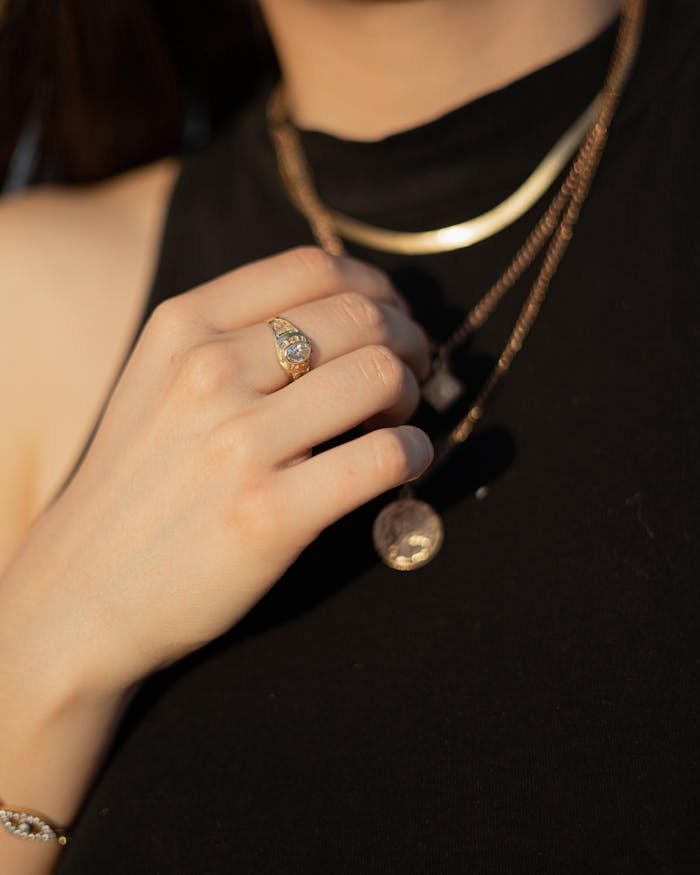 Close-up of elegant gold ring and necklaces worn by a woman. Perfect for fashion and jewelry stock photos.
